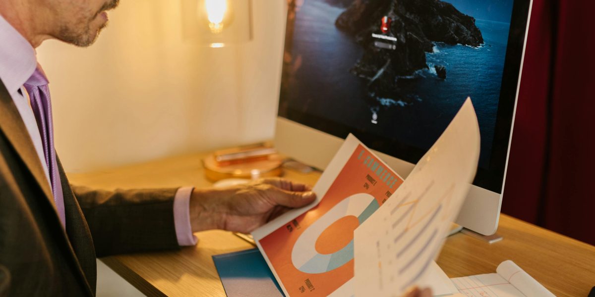 A business professional focused on reports, evaluating the performance and impact of marketing initiatives.