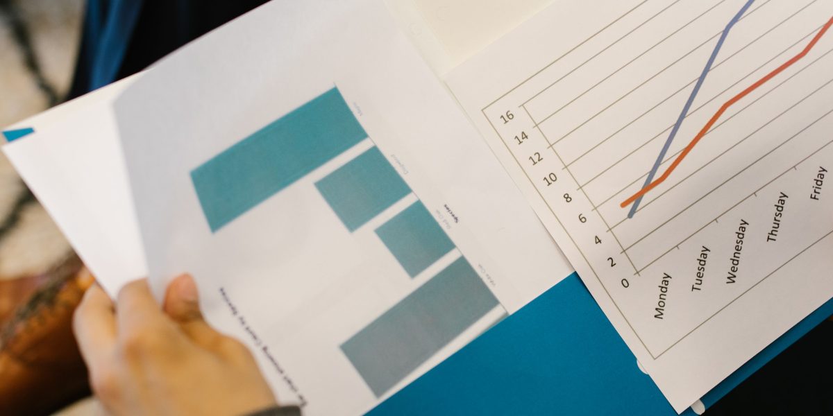A business team reviews charts and graphs on a large screen, analyzing marketing performance data with focus.