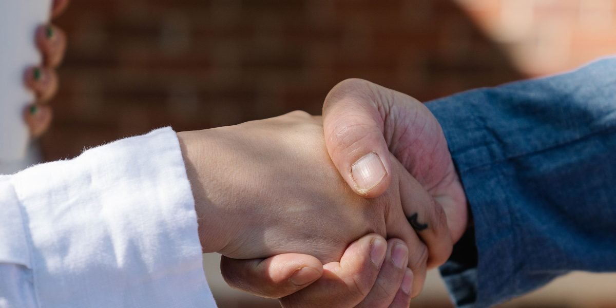 Two professionals shake hands, symbolizing a successful partnership or integrated strategy.