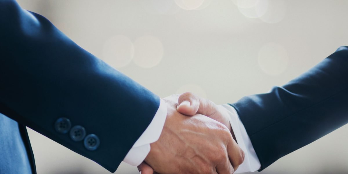 Two business professionals shaking hands, representing the formation of long-term, equity-based partnerships in the creator economy.