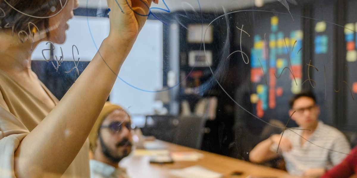A diverse team collaborating around a whiteboard, actively working on defining and refining a new social media policy.