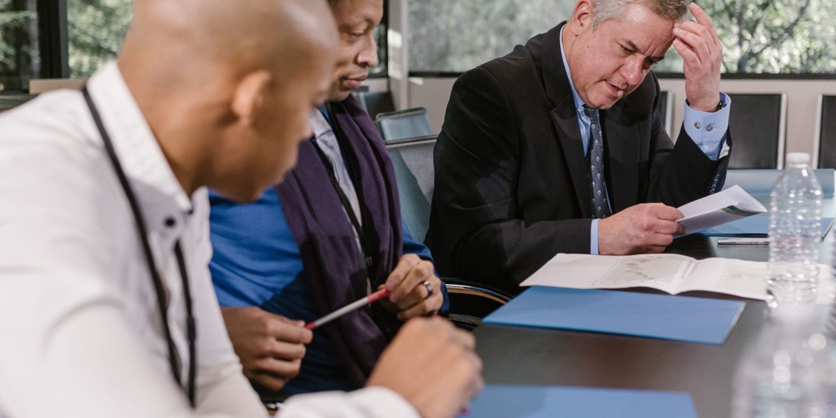 Professionals gathered around a table, meticulously reviewing documents and reports.