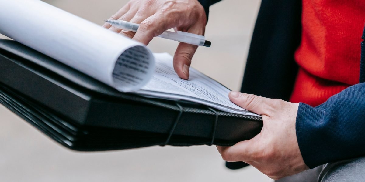 A professional carefully reviewing multiple agency proposals to assess their past work and capabilities.